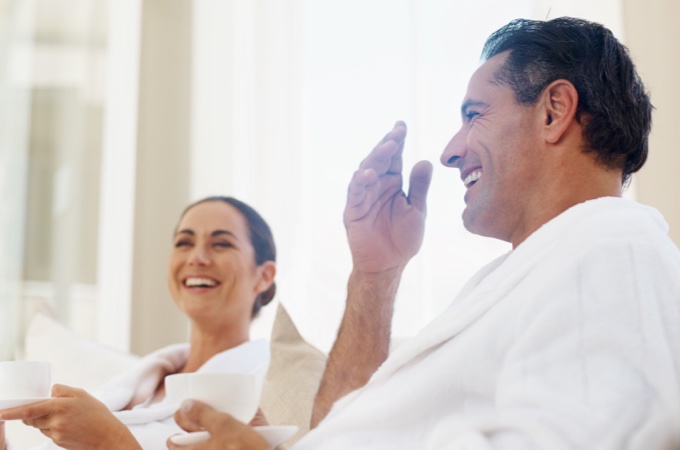 Couple smiling while sitting in robes at spa